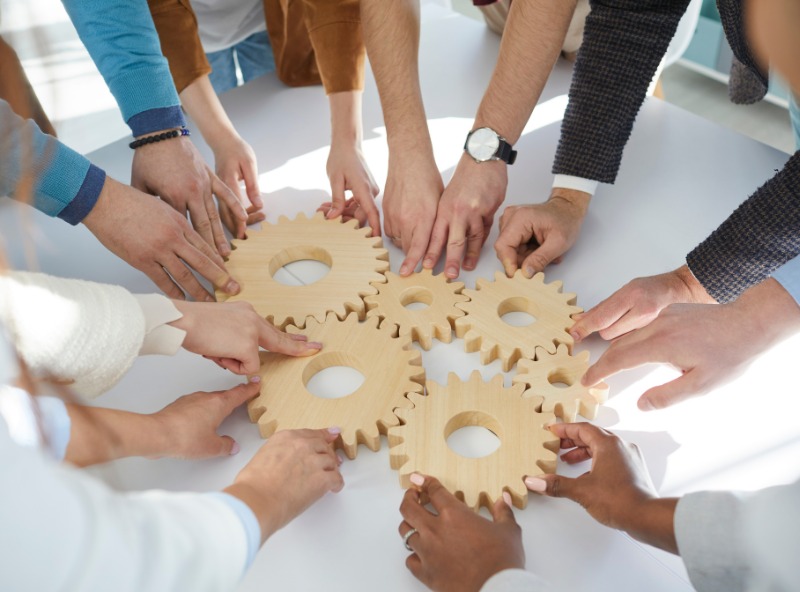 Group of Individuals holding a wheel gear together on a table.